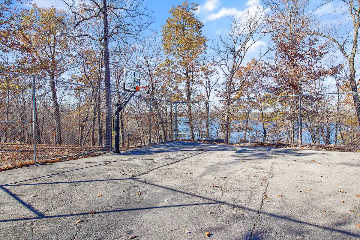 An exterior scene featuring a basketball hoop with a clear view of the lake and surrounding trees. The area invites active play and offers a picturesque backdrop, blending recreational fun with lakeside beauty.
