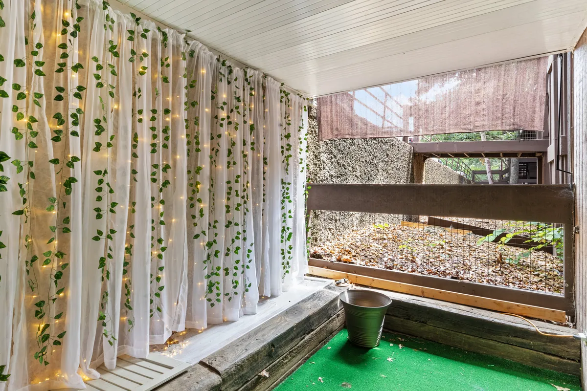 A cozy, nature-inspired corner with leafy patterned curtains, soft fairy lights, a green carpet, and a potted plant. The space is imbued with soothing, gentle light and a sense of calm, perfect for meditation or reading in peace.