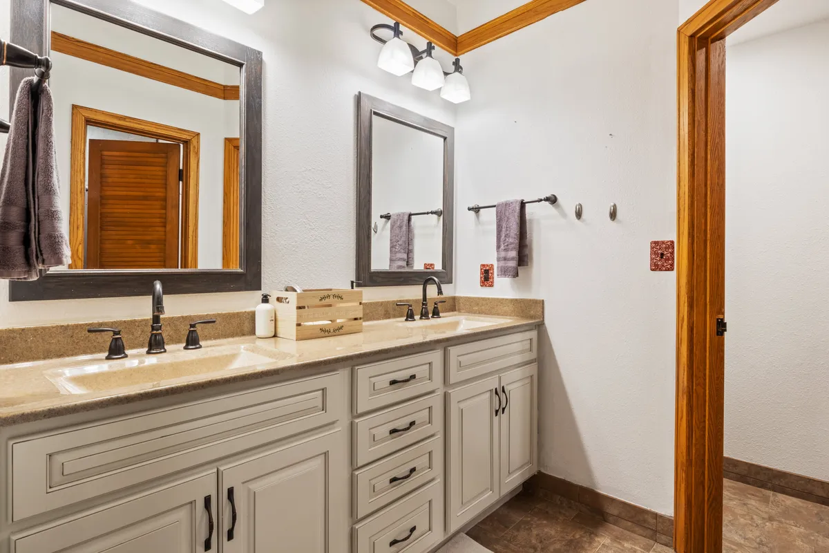 A well-lit bathroom featuring a double vanity with mirrors, elegant light fixtures, and plush towels. The space feels organized, calm, and luxurious—ideal for morning routines or evening wind-downs.