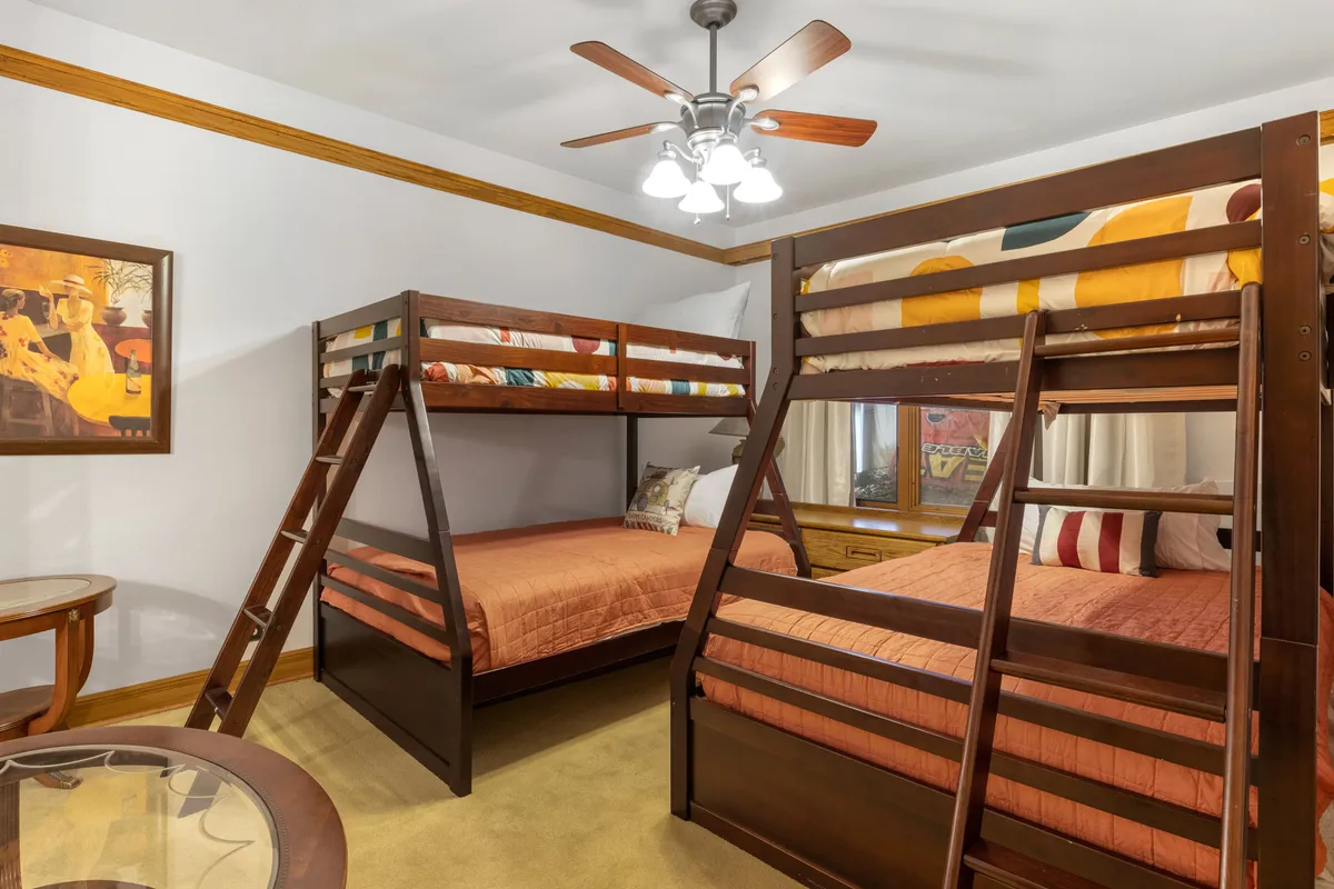 A playful bedroom set up with bunk beds, cheerful artwork, and a ceiling fan. The room exudes a relaxed, family-friendly vibe, perfect for bonding moments and making memories with children or groups.